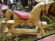 A GOOD ANTIQUE STYLE CARVED PINE ROCKING HORSE on a swing rocker pedestal base and buttoned red
