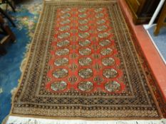 A PAKISTAN MULTAN WOVEN WOOL CARPET, red ground centre with repeating block pattern and multi-