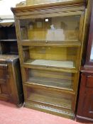 AN OAK GLOBE WERNICKE STYLE FOUR SECTION BOOKCASE with lift-up sliding doors and shaped top and