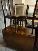 A vintage drop leaf oak dining table together with three splat back dining chairs with drop-in
