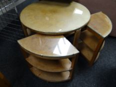 A circular glass topped coffee table with pull-out quarter shelved tables