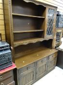 A vintage oak lounge unit with glazed & shelved top above a three-drawer three-cupboard base