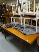 A 1960s G-plan style teak extending dining table with six similar matching spindle back chairs, five