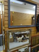 A large grey painted carved framed bevelled wall mirror together with a similar modern gilt framed