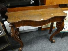 An antique oak serpentine fronted rail back console table