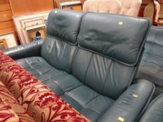 A modern turquoise leather two-seater sofa together with a matching rocking arm chair