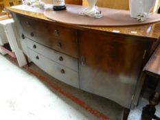 A reproduction mahogany bow fronted sideboard with four drawers flanked by two cupboards on raised