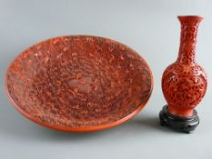 A CARVED CINNABAR STYLE DISH & VASE, the 33 cms diameter dish having central fruit and leaf