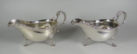 A PAIR OF SILVER SAUCE-BOATS, raised over pad feet with scallop terminals and with feathered rims