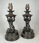 A PAIR OF ANTIQUE METALLIC CHERUB LIGHT-FITTINGS on circular bases, 29cms high