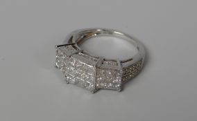 A DIAMOND CLUSTER RING of stepped form and with diamonds to the shoulders in 9ct white gold, 2.5-3ct
