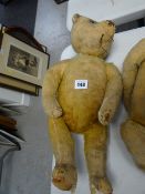 A vintage straw stuffed teddy bear with head movement by turning the the tail
