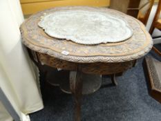 A profusely carved shaped-top Indian-style occasional table with a pierced metal decorated