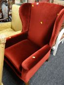 A red velvet upholstered wingback armchair