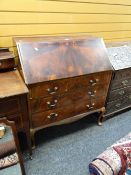 A vintage flame mahogany three-door drop down bureau on raised feet