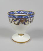 A RARE SWANSEA PORCELAIN EGG CUP decorated with a continuous band of blue and gilded flowers &