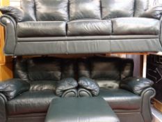 Green leather effect four piece lounge suite of three seater settee, two armchairs and footstool