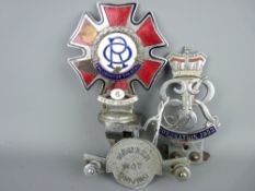 Three vintage car badges including a Spencer London 'The Order of the Road' enamel badge with six