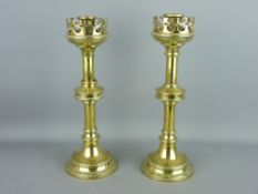 A PAIR OF GOTHIC STYLE BRASS CANDLESTICKS with pierced gallery drip pans, 31 cms high