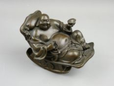 A 20th CENTURY BRONZE FIGURE OF BUDAI reclined in a rocking chair, 12.5 cms high, 15 cms long