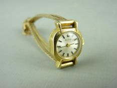 AN EIGHTEEN CARAT GOLD CASED BULOVA LADY'S WRISTWATCH with yellow metal bracelet strap