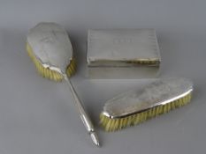 A SILVER CIGARETTE BOX and two silver backed brushes, 13 cms long, Birmingham 1929 the box
