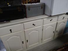 A modern white painted sideboard with four drawers above a four door cupboard base