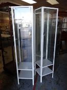 Two narrow tall metal glass shelved display cabinets