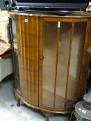 A vintage bow fronted walnut veneered two-door glass display cabinet