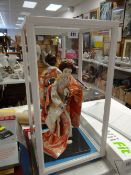 A cased Japanese doll figure playing a drum