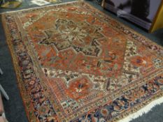 A large multi-coloured Persian rug with central decoration within a diamond & patterned border,