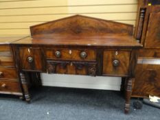 A late nineteenth century mahogany railback sideboard on raised legs, two drawers flanked by a