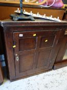 An antique oak hanging corner cupboard with brass fittings