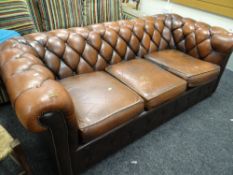 A brown leather button back three-seater Chesterfield sofa