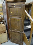 An antique oak two-door standing corner cupboard