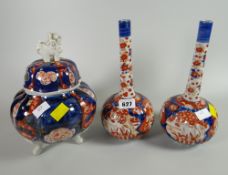 A pair of Oriental Imari decorated narrow necked vases together with a lion handled lidded pot