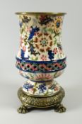 A continental vase on raised brass base with lion paw feet