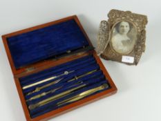 A believed silver pierced work photograph frame together with a wooden cased set of drawing