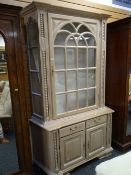 A modern limed oak glass top display cabinet, two-drawer & two cupboard base, 214 x 130 x 50cms