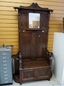 An early twentieth century oak mirror hall stand with lifting seat & carved lion arm decoration, 210