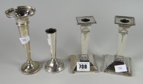 A pair of hallmarked silver short decorated candlesticks together with a bud vase & another