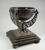 AN UNUSUAL TABLE CENTREPIECE with white metal bowl raised over an openwork metallic bracket on a