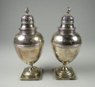 A CASED PAIR OF HEAVY QUALITY SILVER CASTERS of ovoid form over square bases with torch finials,