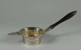 AN UNUSUAL SILVER TEA-STRAINER with extended ebonised handle and relief decorated with two unknown