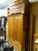 A honey pine carved decorated double wardrobe with a two-drawer base together with a three-drawer