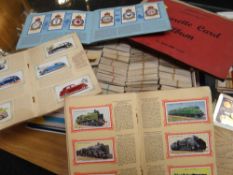 A box full of loose cigarette cards together with three small cigarette card albums