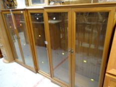 A pair of two-door modern glazed cabinets together with a matching single-door cabinet