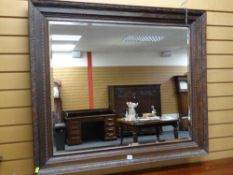 A large carved oak bevel glass wall mirror