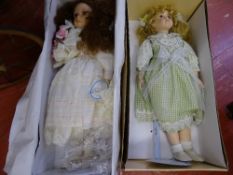 Doll with green check dress and doll with a cream silk dress, each on metal stands and boxed