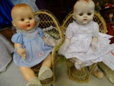 Composition headed rosebud doll and another similar, each sitting on a peacock straw seat